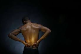 Black man with lower back pain thinking of seeing a Massage Therapist.