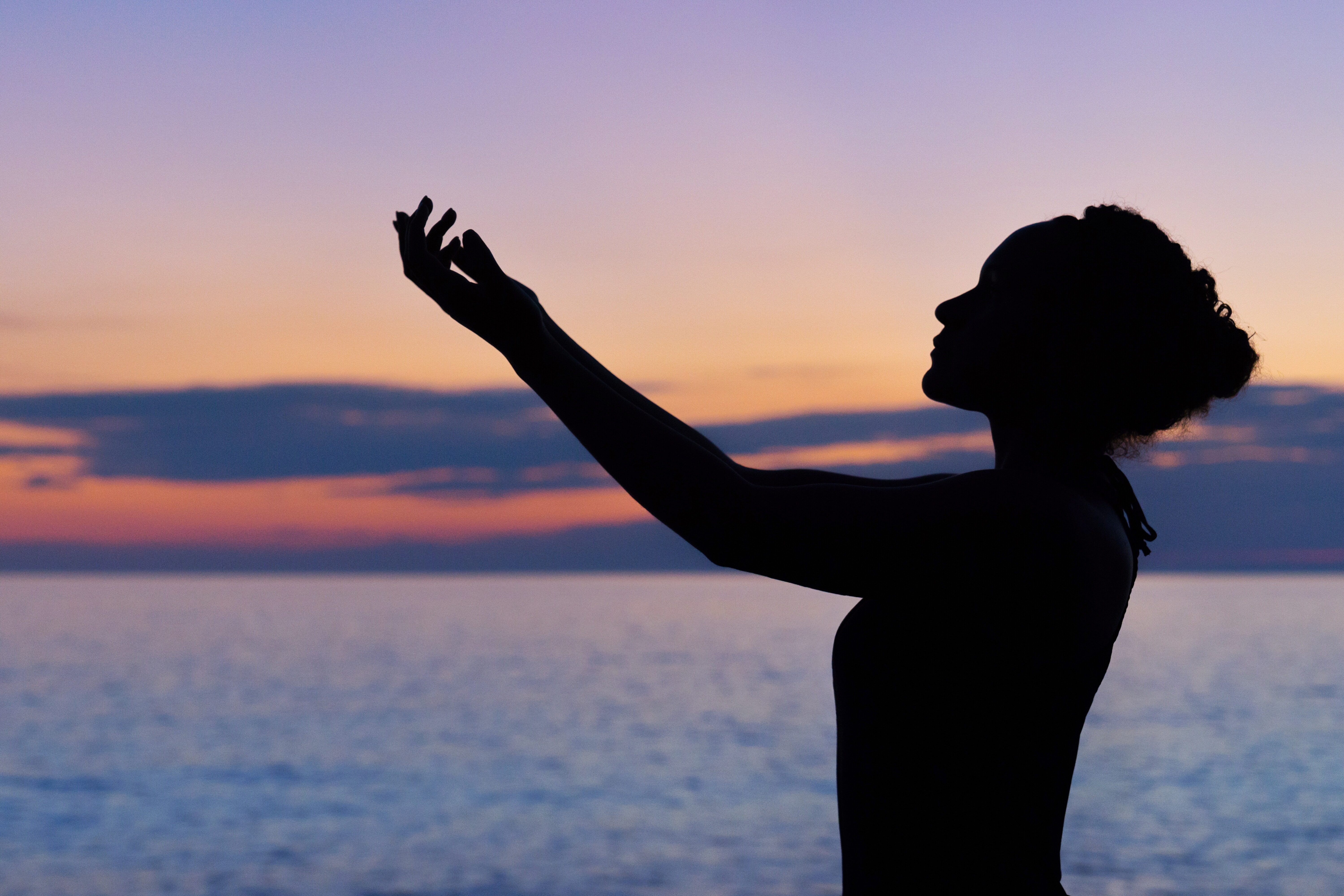 silhouette of woman raising her right hand whilst the sunsets because she overcame a loss.