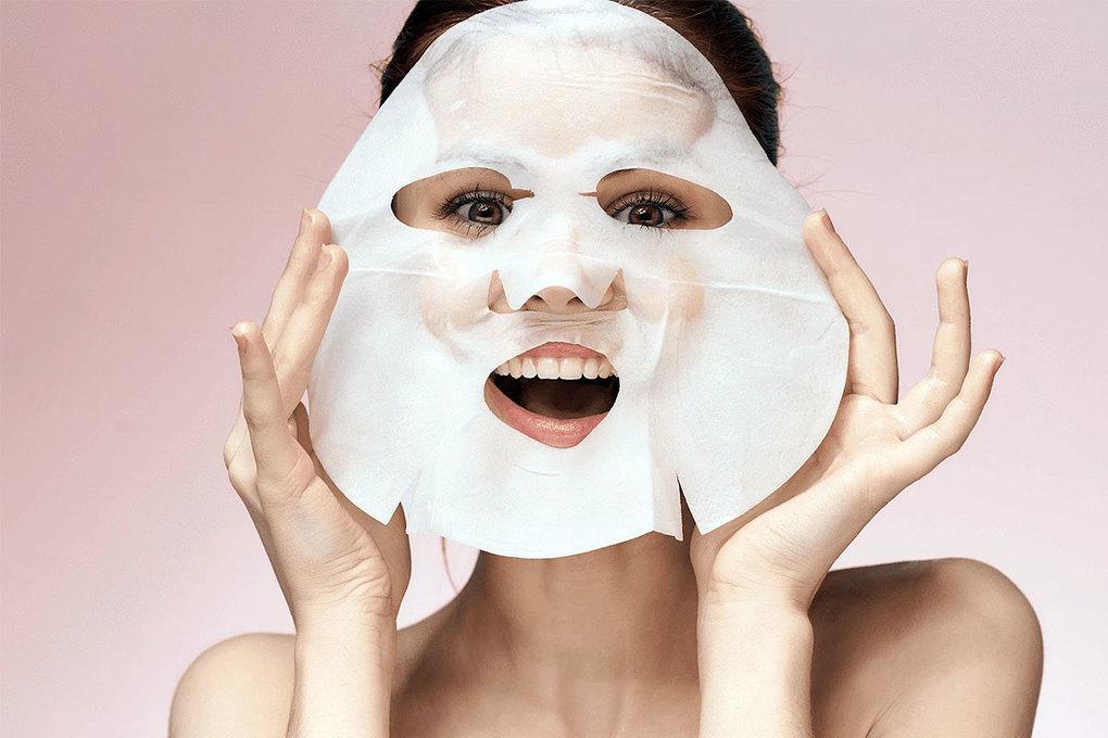 A woman with a sheet mask on happy with the benefits of a sheet mask.