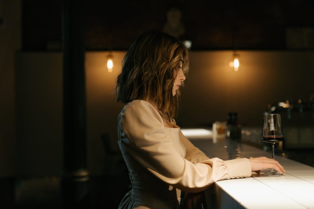 Coley Awakend shows a woman in white long sleeve shirt sitting by the table in deep thought about dating and loneliness.