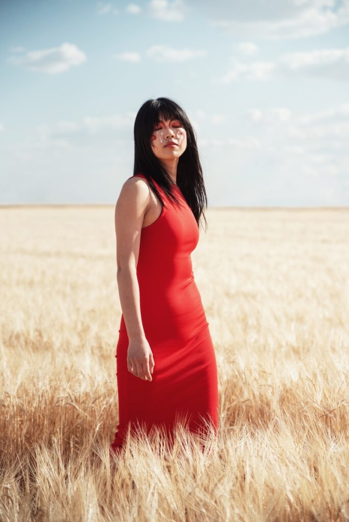 The art of slowing down -A woman in a red dress standing in a wheat field slowing down to soak in the moment.